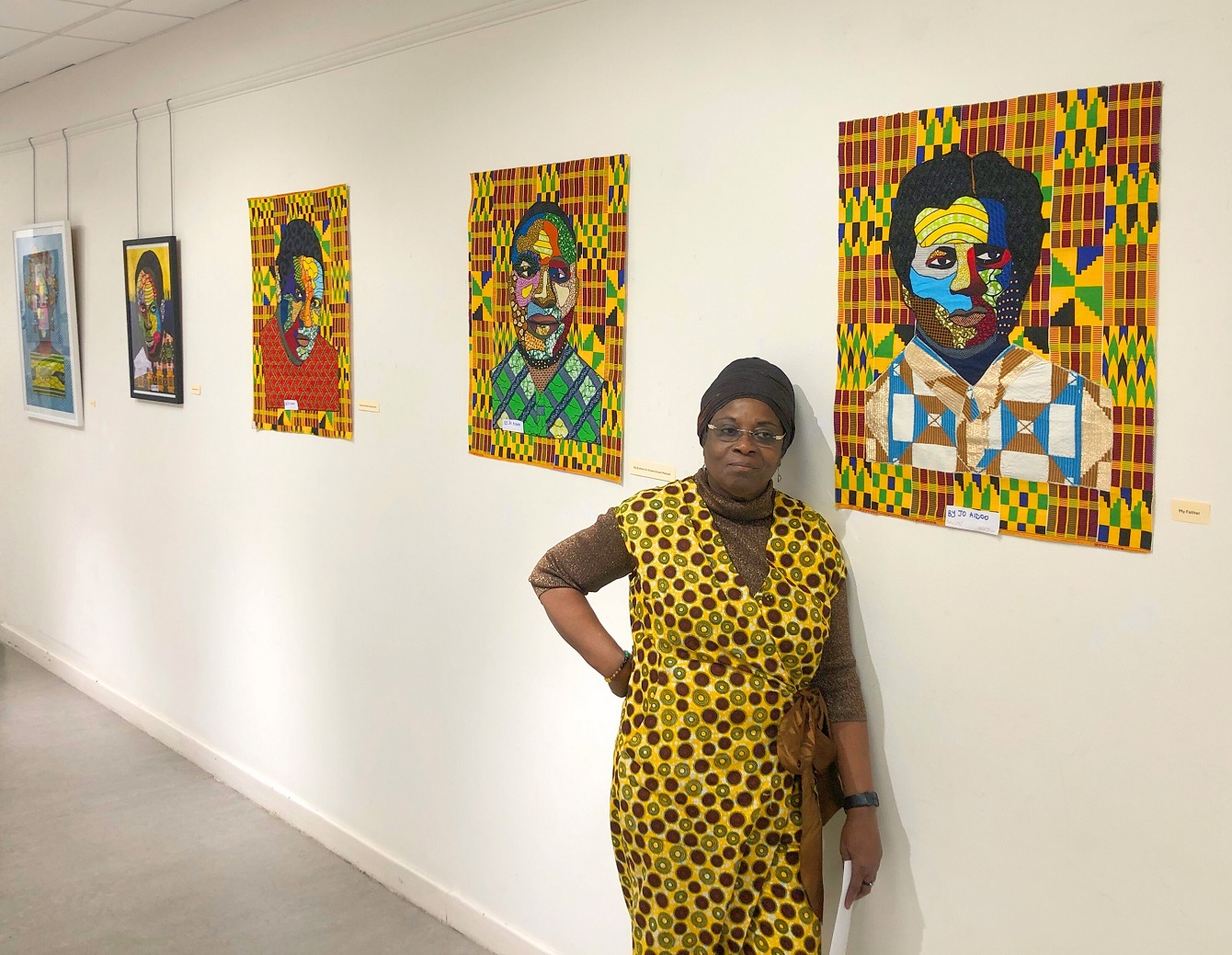 Woman in a yellow dress standing in front of colourful artworks in a gallery space