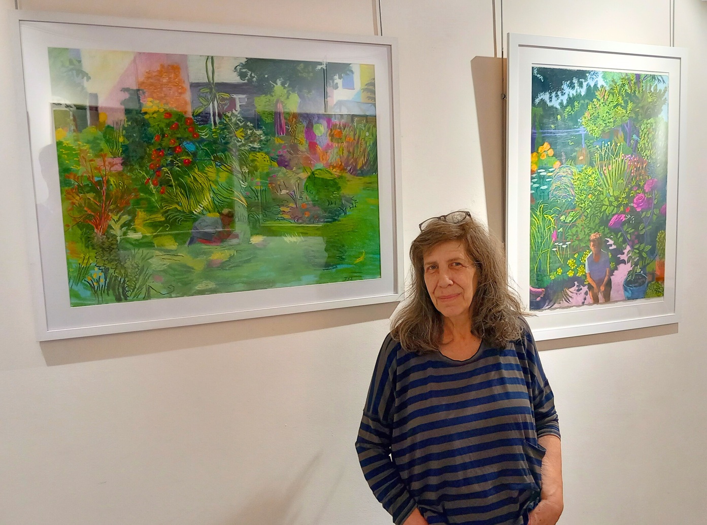 Woman standing in front of two big, colourful artworks hung on a white wall in gallery.